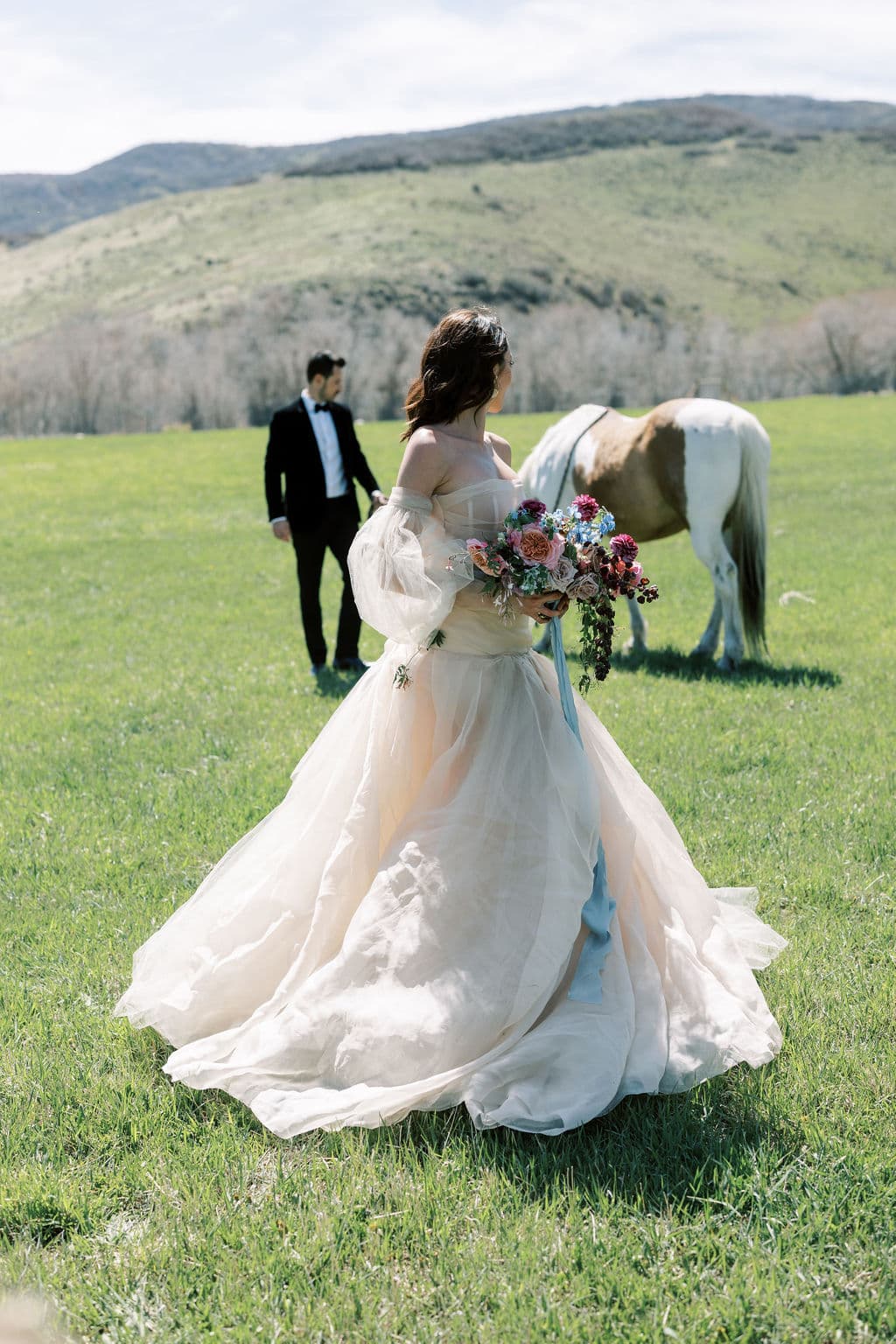 A groom kissing his bride's temple, her arms full of a wildflower bouquet, editorial wedding photography by Christopher Cook