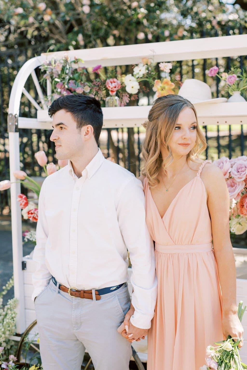 An engaged couple in front of a flower cart during their Charleston engagement session