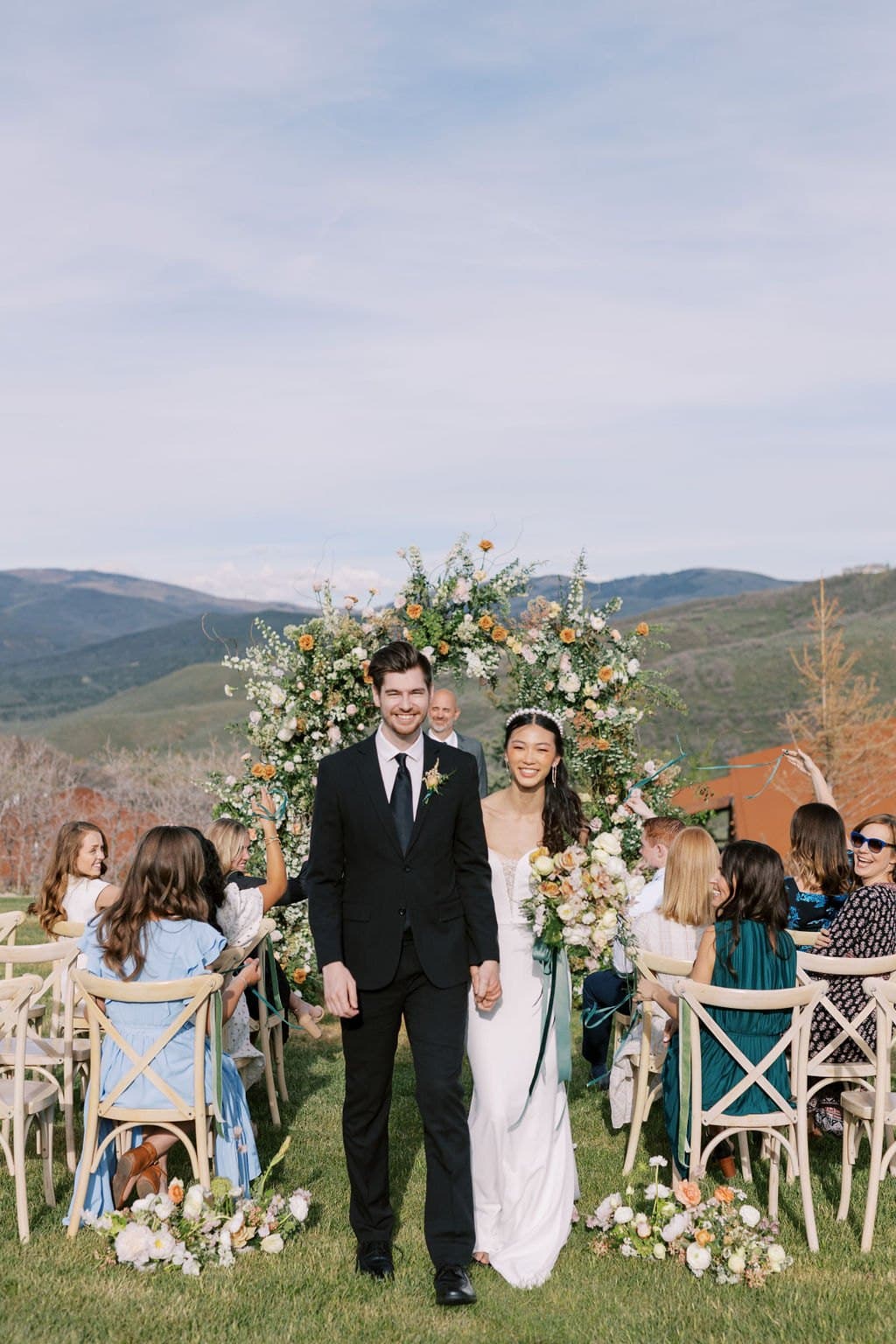 A bride and groom walking back up the aisle past their guests at a Park City mountain wedding