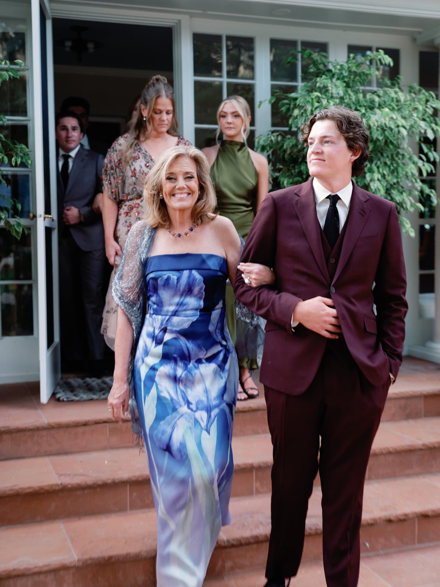 Jake walking down the steps arm in arm with his mother before the ceremony