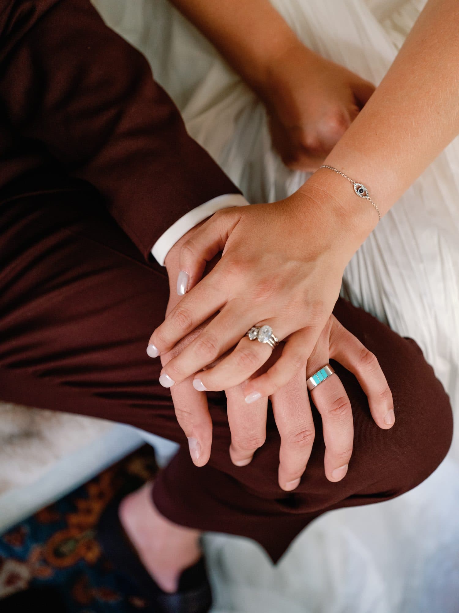 Lauren’s hand resting over Jake’s on his knee, both wedding rings on