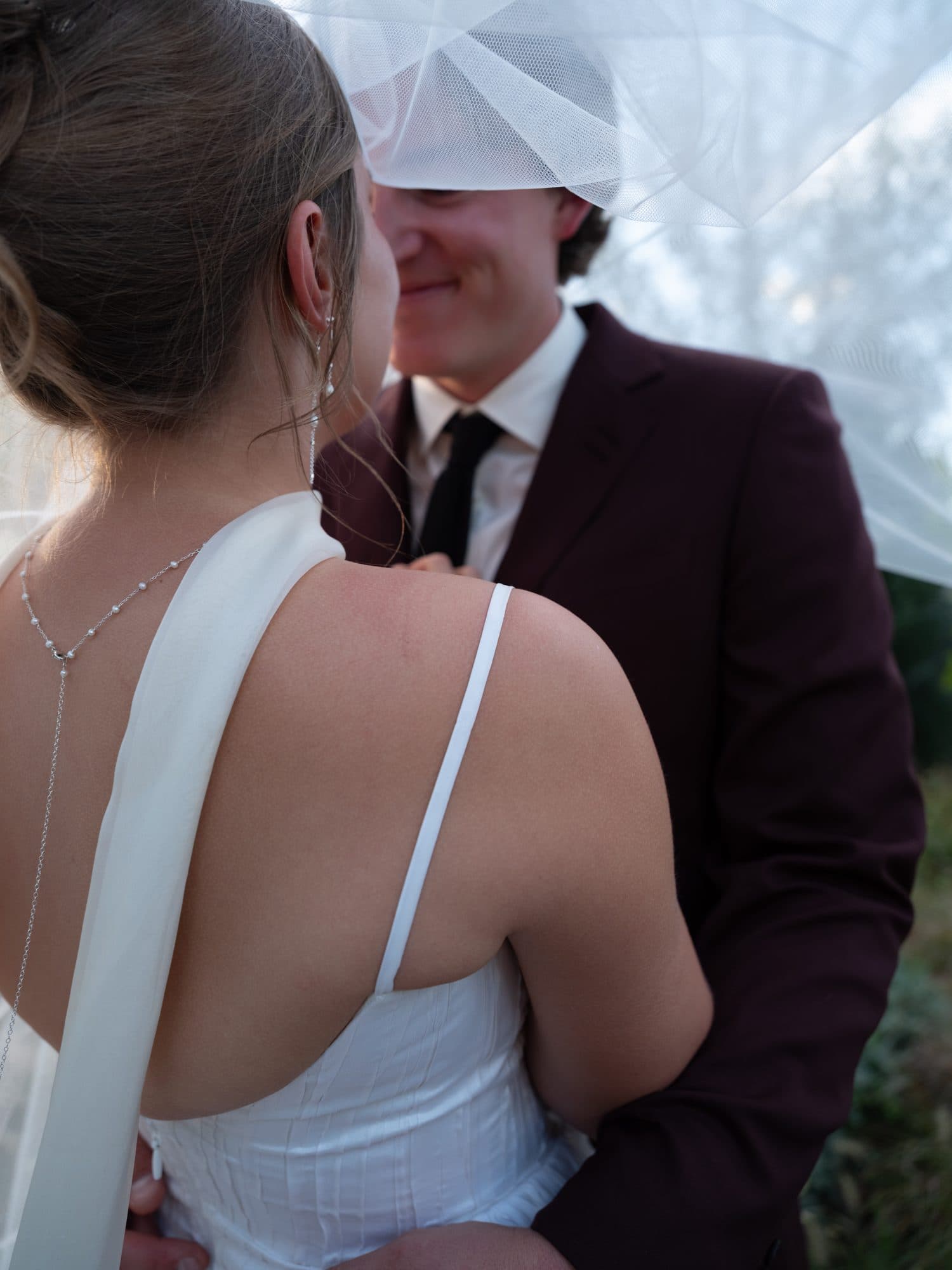 Lauren and Jake close together under her veil, his face half hidden by the tulle