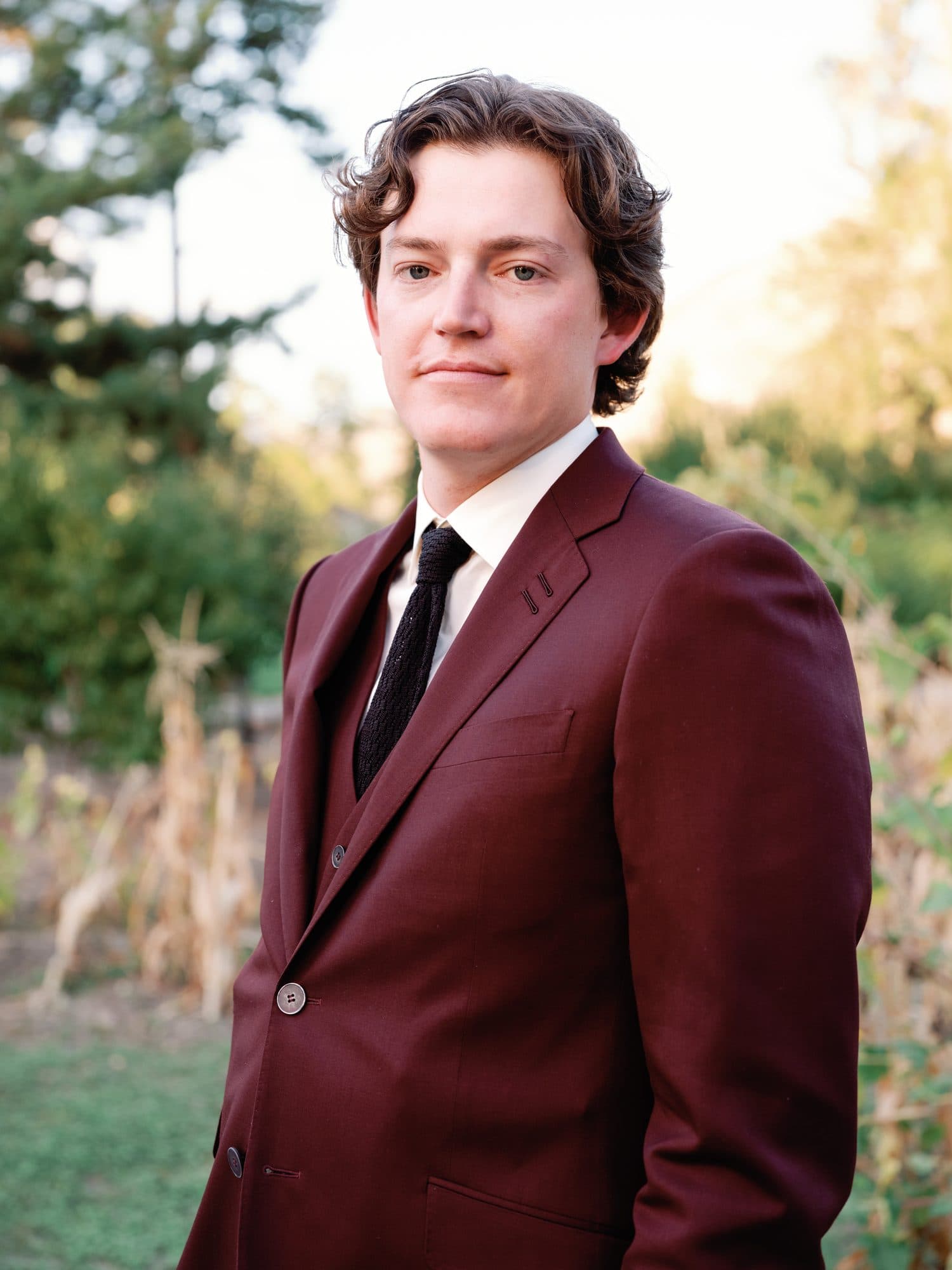 A portrait of Jake in his burgundy suit in the evening light