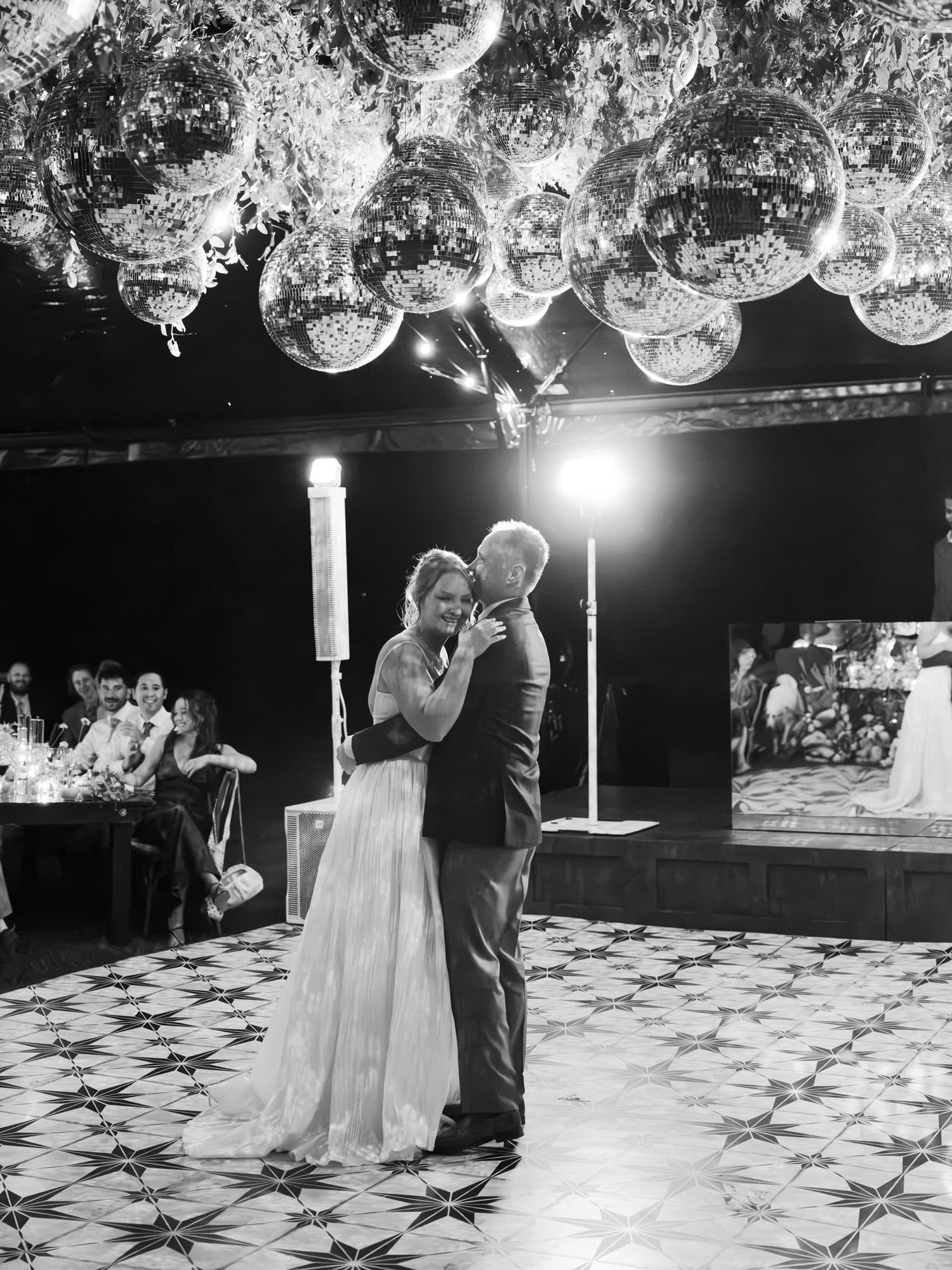 Lauren dancing with her father beneath a ceiling of disco balls, in black and white