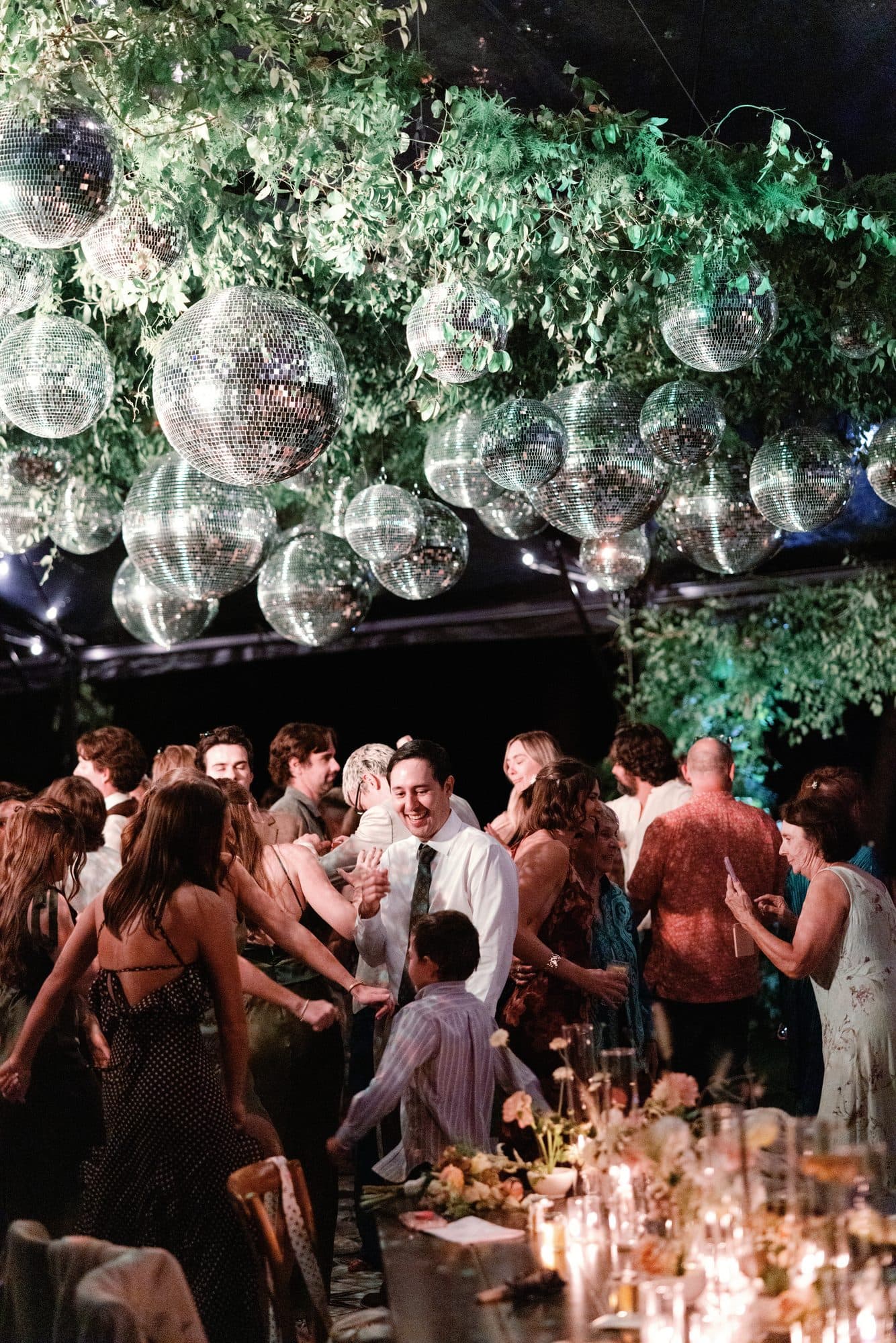 The dance floor full beneath a ceiling of disco balls and greenery