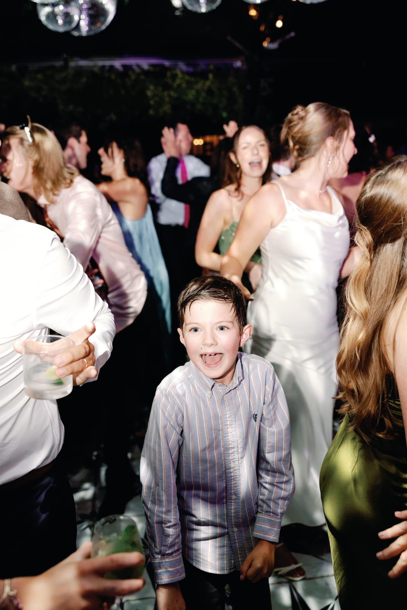 A young guest grinning at the camera in the middle of the dance floor