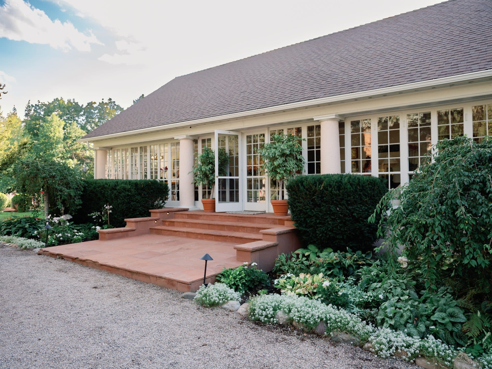 The long white house with walls of French windows, terracotta steps and potted citrus at the door