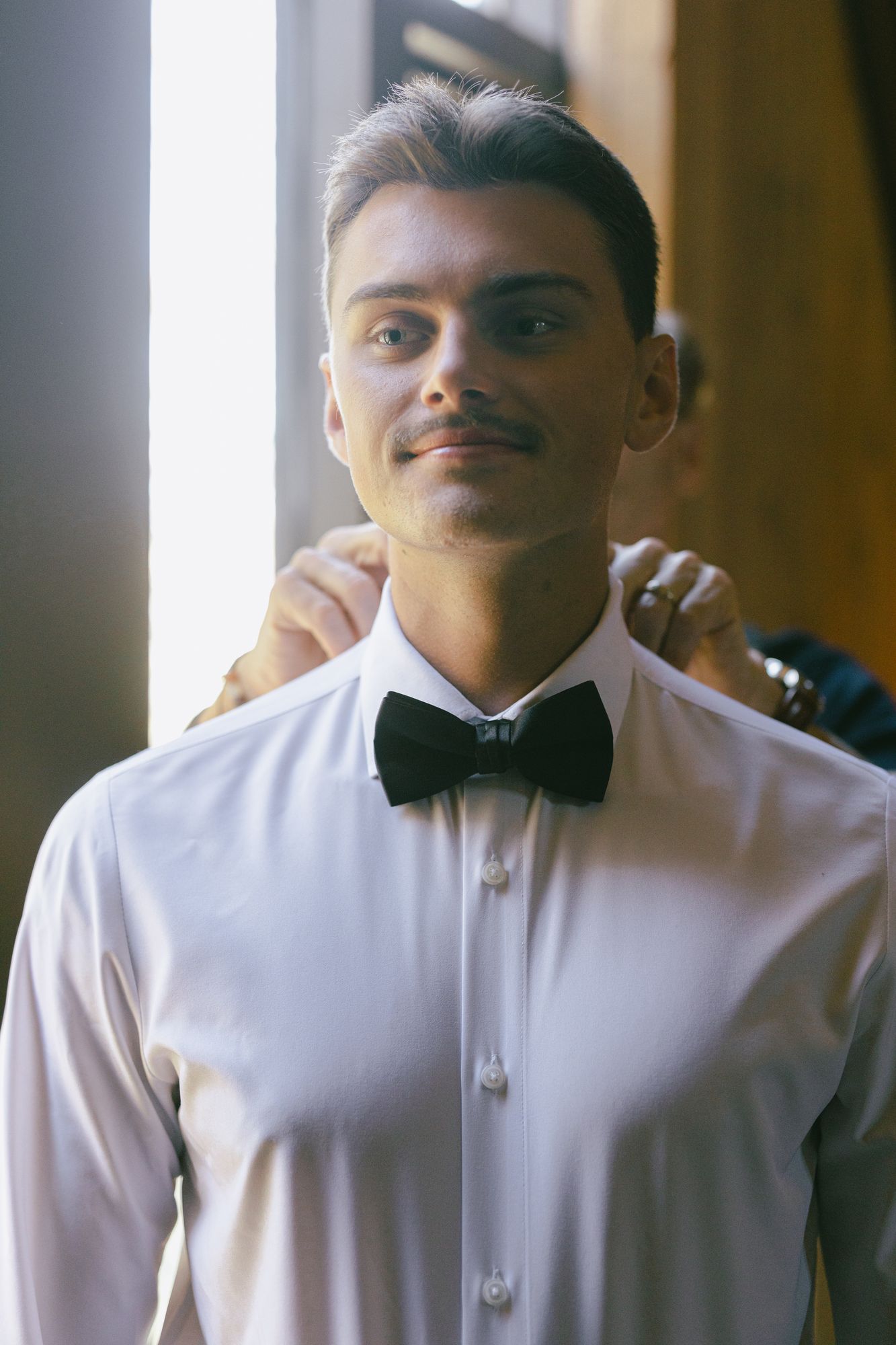 Kyle in a white dress shirt and black bow tie before the ceremony, photographed in black and white