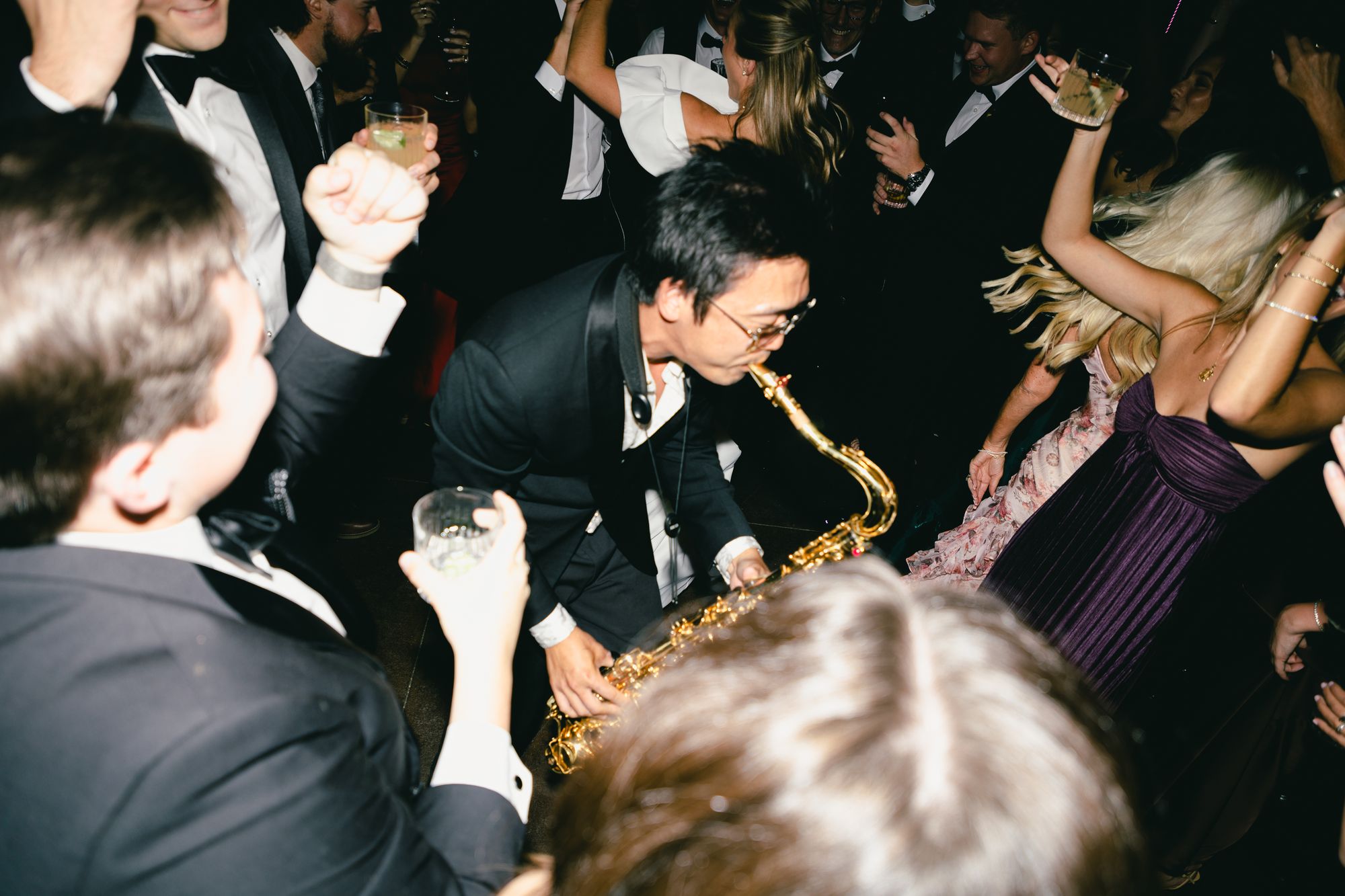 The saxophonist playing out in the middle of the dance floor surrounded by guests