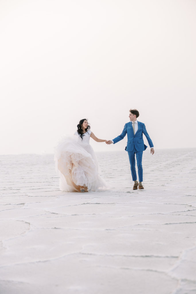utah Bride and groom hold hands on salt flats